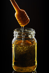 Honey jar with dipper and flowing honey
