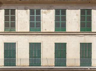 Architecture detail, symmetrical facade green windows and balconies with blinds closed in Palma de Mallorca, Balearic Islands, Spain.