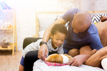 African American family of two playing with a dog pet in bedroom