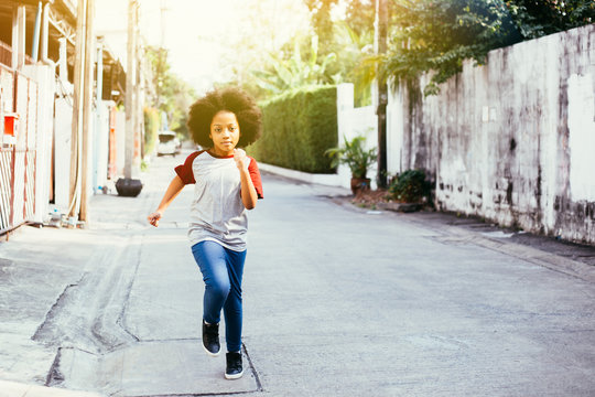 African American Kid Running On The Street In Urban City