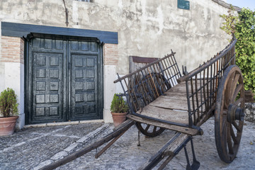 Fototapeta na wymiar Rural scene, street view, ancient door facade house and old carriage in the village of Chinchon, province Madrid, Spain.