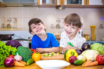 Healthy eating. Happy children prepares and eats vegetable salad in kitchen