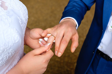 Closeup hand of a bride put on engagement ring on the finger of groom