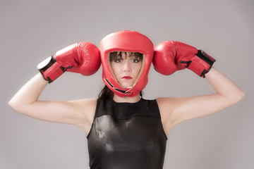 Woman boxer with an facial expression wearing a red headguard and red boxing gloves, Circa 2018