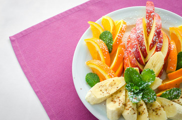 Bananas, apples , pineapple, oranges. Assorted fruits on the plate with pink background. Flat lay. Vegan. Healthy food concept.