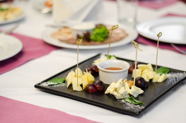 Fototapeta na wymiar Assorted cheeses with honey and nuts in the black plate in restaurant
