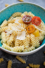 Close-up of fusilli served with cherry tomatoes and parmesan cheese, selective focus, vertical shot