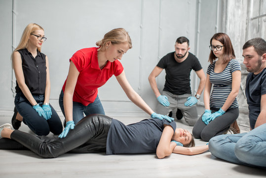 Young woman instructor showing how to lay down a woman during the first medical aid training indoors