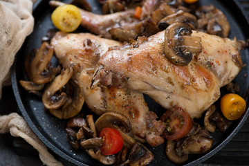 Roasted rabbit meat with champignons and fresh cherry tomatoes, closeup, selective focus