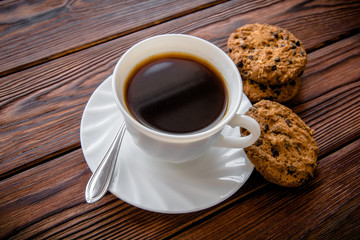     A cup of hot coffee stands on a wooden table 