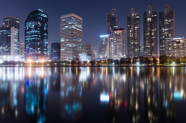 Fototapeta na wymiar modern building bright in night city with skyline symmetric water mirror reflection. night cityscape concept.