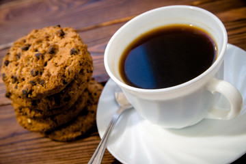 A cup of hot coffee stands on a wooden table 