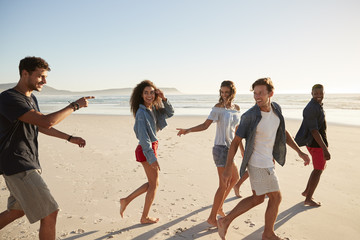 Obraz premium Group Of Friends On Vacation Walking Along Beach Together