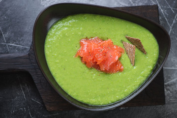 Bowl of cream-soup with green peas topped with salmon fillet, view from above, horizontal shot