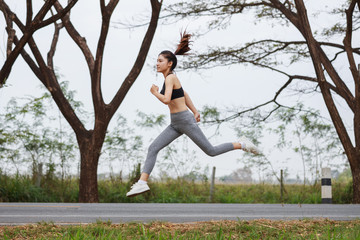 sporty woman running and jumping in park