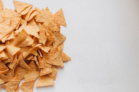 Pile of delicious crispy nachos of out pack on white background, traditional Mexican cuisine