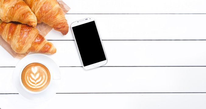 phone croissant coffee view from above wooden white background