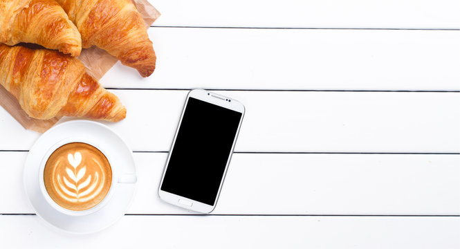 phone croissant coffee view from above wooden white background