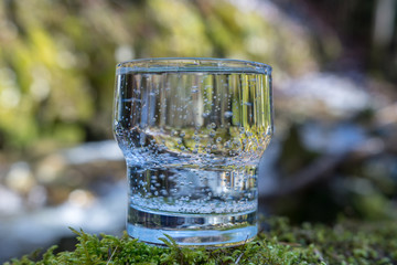 Glas gefüllt mit Wasser vor Fluss in der Natur