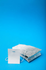 Close-up, label and tea bag on blue background, vertical. Empty space for text.
