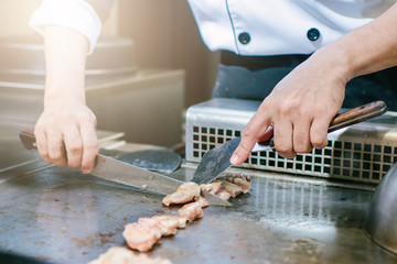 Hand of man take cooking of meat with vegetable grill, Chef cooking wagyu beef in Japanese teppanyaki restaurant