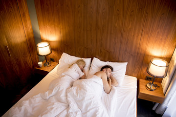 Young adult heterosexual couple on bed in bedroom