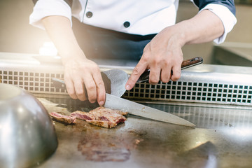 Hand of man take cooking of meat with vegetable grill, Chef cooking wagyu beef in Japanese teppanyaki restaurant