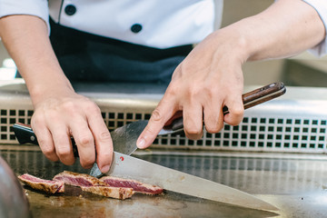 Hand of man take cooking of meat with vegetable grill, Chef cooking wagyu beef in Japanese teppanyaki restaurant