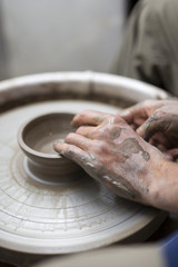 Male artist makes clay pottery on a spin wheel