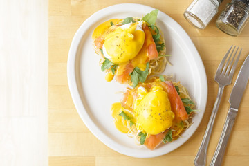 Egg Benedict with smoked salmon, soft window light, selective focus. Juicy Egg Benedict for brunch on the wooden table. Top view