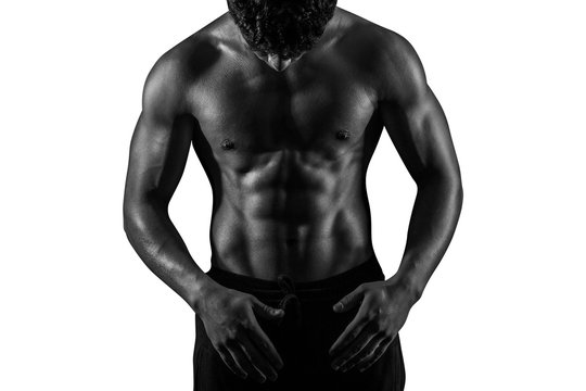 Highly retouched black and white fitness model and bodybuilder. Looking to himself. Posing abs and chest. Concept of power, energy and self-confidence.  Isolated on white background. Copy space.