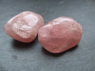 Pierres roulées de quartz rose posées sur une ardoise
