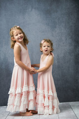Fototapeta na wymiar Silly Sisters Siblings in Pink Dresses