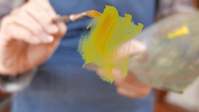 a painter covers a glass with yellow paint