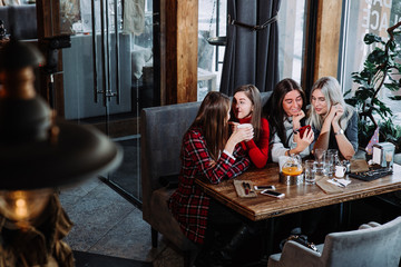 four friends look at the phone and laugh