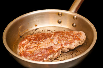 Ramp steak is fried on a steel frying pan.