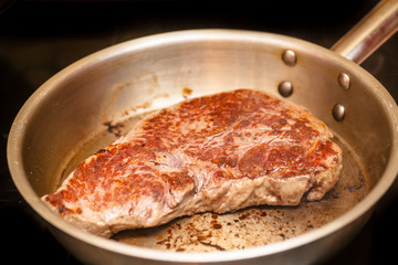 Ramp steak is fried on a steel frying pan.