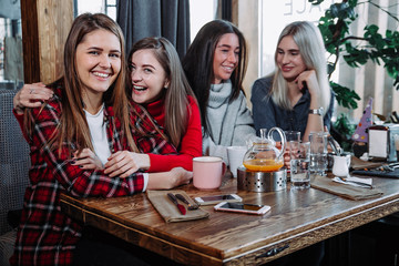 four friends in the cafe look at the camera and laugh