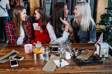 four friends in the cafe look at the camera and laugh