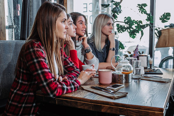 Side view of a Four smiling friends sitting by the table in cafe