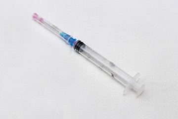 One syringe with cap and needle after using on the white bckground