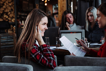 beautiful young businesswoman talking on the phone in a cafe and smiling