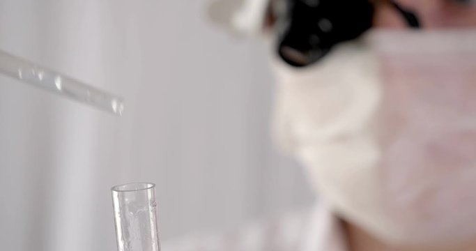Laboratory work, a woman doctor holds a test tube, in a medical mask and professional glasses, a magnifying glass, takes an analysis from a test tube in blue rubber gloves, analysis, blood, DNA, a tes