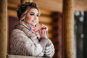 Fototapeta na wymiar Beautiful girl in fur coat at a wooden house