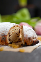 freshly baked cake with sweets, raisins and candied fruits, sprinkled with powdered sugar on a gray table with pink tulips