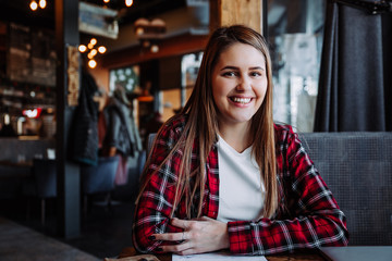 beautiful brunette smiling at camera sitting in cafe