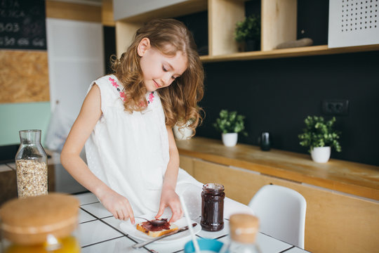 Little girl making breakfast on the table in the kitchen 