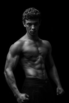 Highly retouched black and white fitness model and bodybuilder, Looking and posing abs and chest. concept of power, strength and self-confidence. black background.