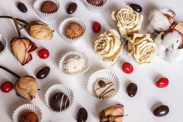 dry rose petals, chocolate sweets and nuts on white background