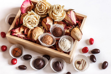 dry rose petals, chocolate sweets and nuts on white background